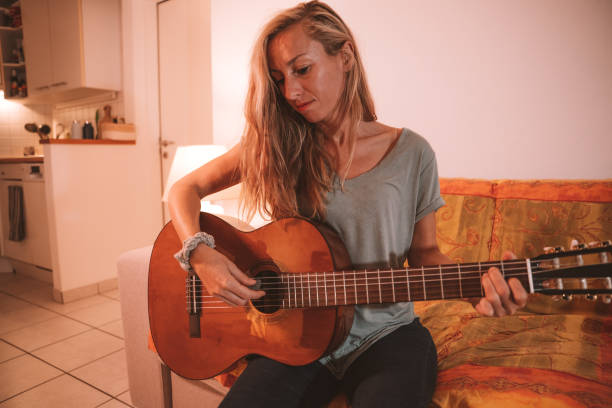 istock Woman plays guitar at home 1297814646