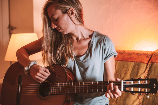 istock Woman plays guitar at home 1297814647