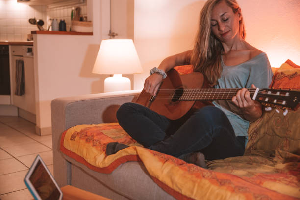 istock Woman learns guitar online from digital tablet 1297814758