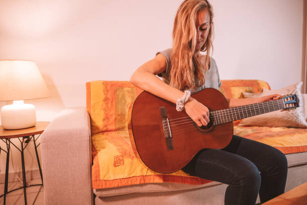 istock Woman plays guitar at home 1297814759