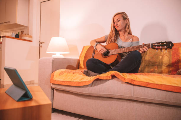 istock Woman learns guitar online from digital tablet 1297814809