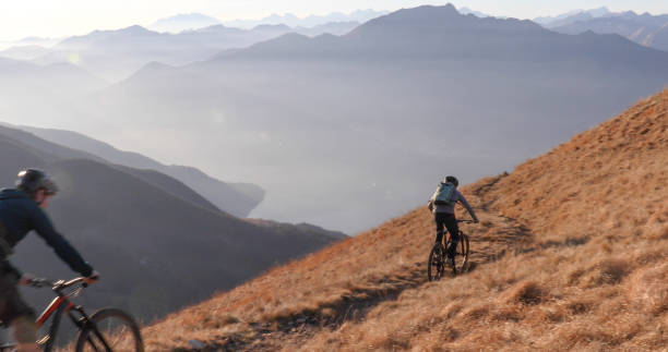 istock Mountain bikers ride down grassy mountain ridge in the morning 1297817552