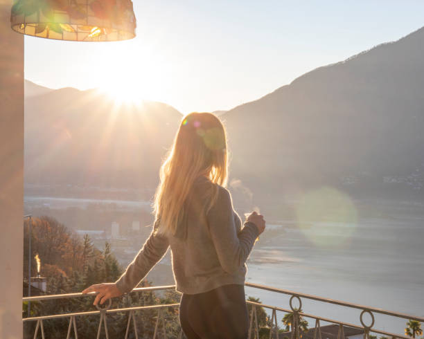 Young woman relaxes on balcony at sunrise stock photo