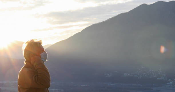 istock Man wearing protective face mask relaxes outside at sunrise 1297817821