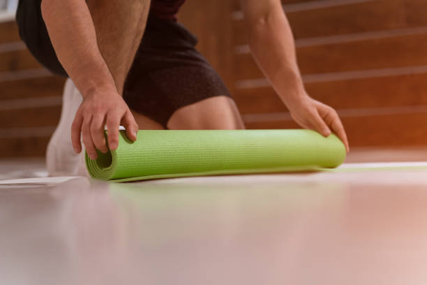 istock Wrapping UP after training a roll mat athletic man, preparing a place for sports. Determined guy doing physical training. Strong handsome young man, in a gym 1297817937