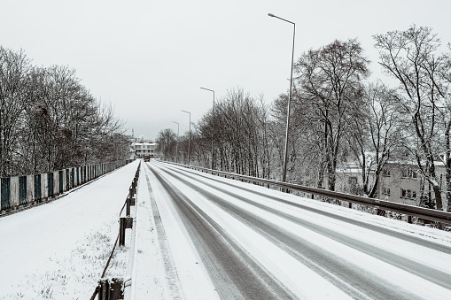 A snow-covered road down from the top of the railway viaduct, on the left a pedestrian footpath.
