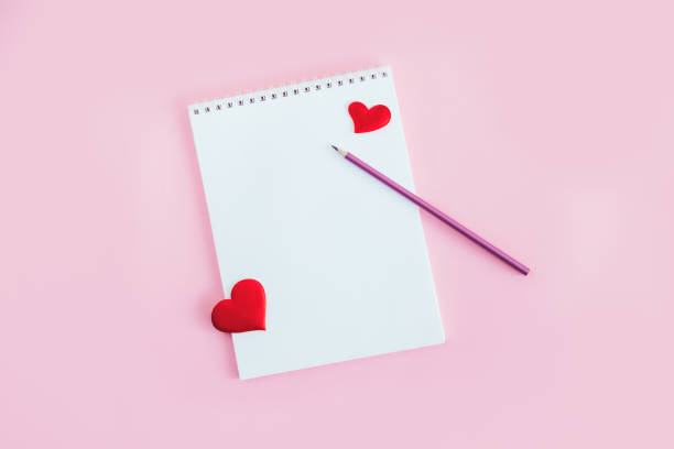 istock Notebook with blank page, pencil and red hearts on a pink background. 1297820057