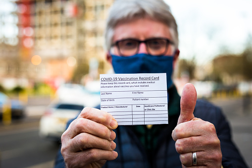 Senior man holding covid-19 vaccination record card