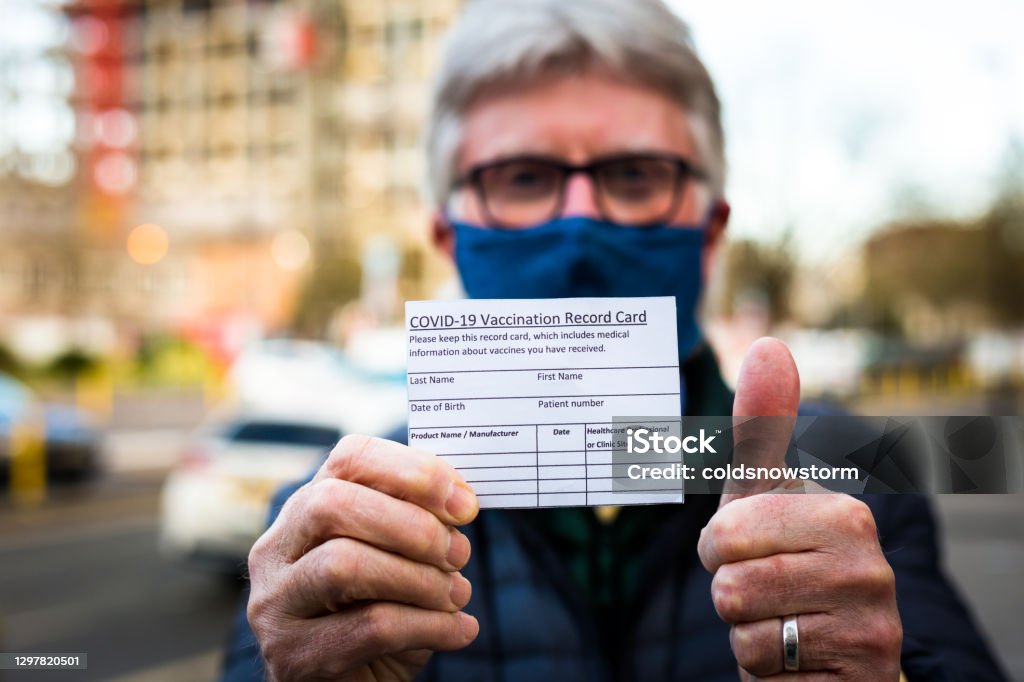 Starszy mężczyzna posiadający kartę zapisu szczepień covid-19 - Zbiór zdjęć royalty-free (Szczepionka na COVID-19)