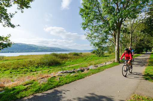 Bala; UK: Sep 20, 2020: Cyclists enjoy riding along an asphalt trail beside Bala Lake, on a sunny Sunday in September.