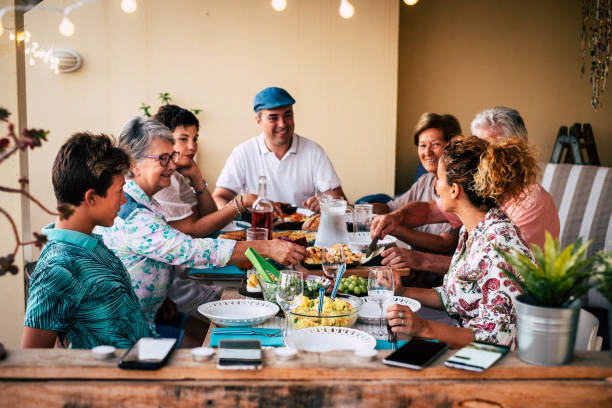 group of people friends or family enjoy together dinner or lunch sitting at the table with food and drinks - happy people caucasian celebrate and having fun at home eating and drinking - group of objects travel friendship women imagens e fotografias de stock
