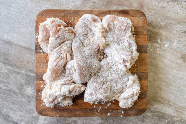 floured raw chicken portions on cutting board stock photo