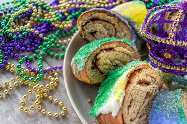 Sliced Mardi Gras king cake surrounded by colorful beads stock photo