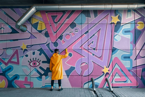 artista callejero pintando grafitis coloridos en la pared - pintura producto artístico fotos fotografías e imágenes de stock