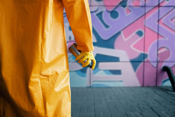 cropped image of street artist with spray paint can in hand standing near the wall - graffiti men wall street art imagens e fotografias de stock