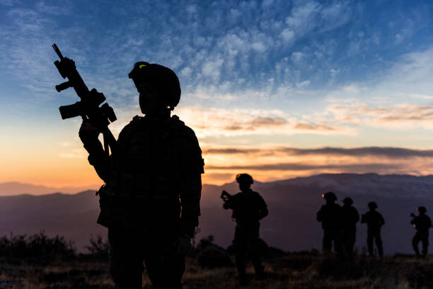 Female Soldier standing at sunset during a Military Mission Female Soldier standing at sunset during a Military Mission terrorism stock pictures, royalty-free photos & images