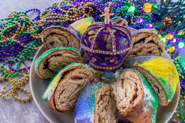 нарезанный марди гра царь торт с ребенком в окружении красочных бусин - mardi gras new orleans mask bead стоковые фото и изображения