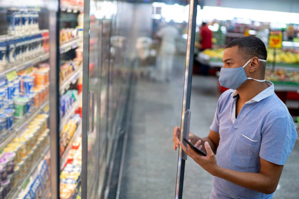 istock Man wearing face mask opening refrigerator in a supermarket 1297824433