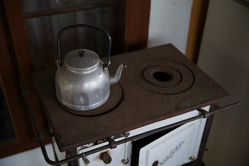 White old vintage retro kitchen stove and an aluminum tea pot.