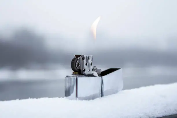 Flaming lighter zippo. Lighter on snow in the winter. Wallpaper.