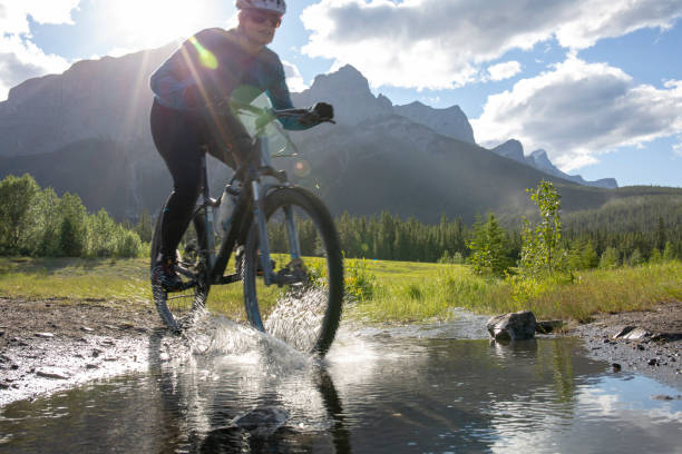 istock Woman mountain biker rides across a mountain stream 1297831071