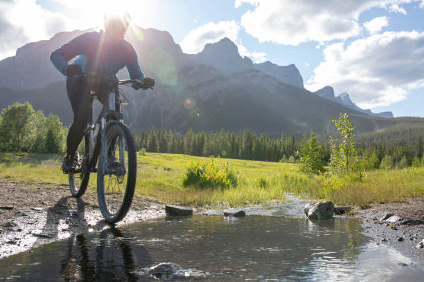 istock Woman mountain biker rides across a mountain stream 1297831095