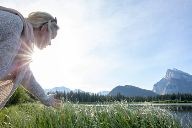 Woman runs hand through tall grasses on lakeshore
