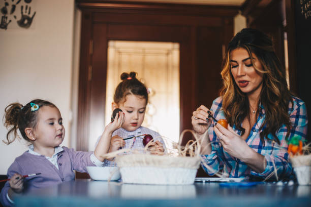 istock Mom is showing her daughters how to paint Easter eggs. 1297831525