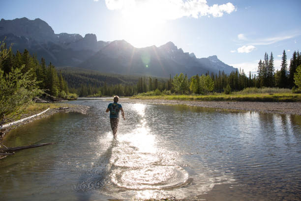 istock Man runs across shallow water into sunrise over mountains 1297832237