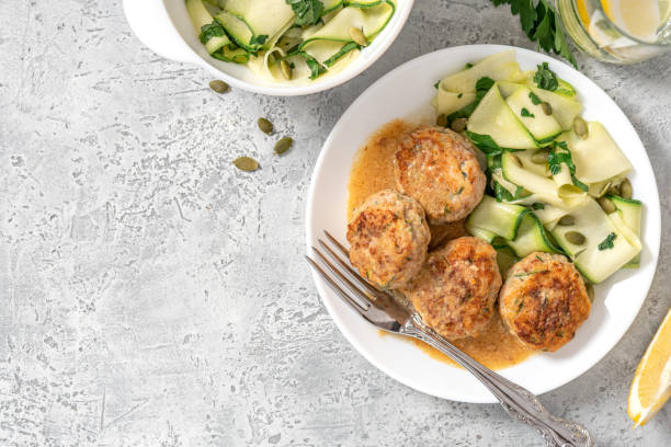 Chicken meatballs with zucchini in a plate top view. Chicken meatballs with raw zucchini in a plate on a gray concrete table top view. Copy space for text. Tasty and dietary food. chicken balls stock pictures, royalty-free photos & images