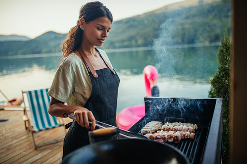 Female holding skewer with meat and putting on barbecue