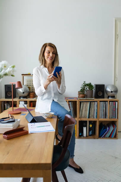 istock Happy Mature Woman Using a Smartphone at the Office 1297835385