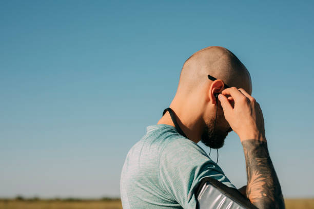 Outdoor cardio workouts: a bald handsome man in sportswear going for a run in nature, a close up