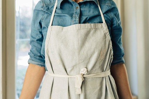 Unrecognisable cropped woman artisan standing and wearing apron.