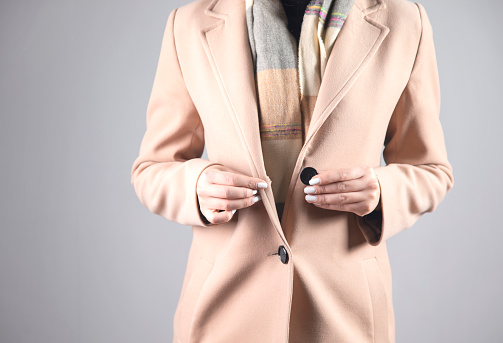 young woman with coat button on grey background