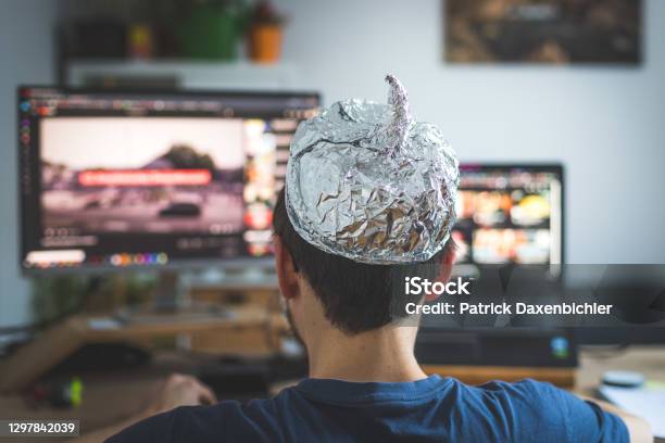 Conspiracy Theory Concept Young Man Is Wearing Aluminum Head Sitting In Front Of The Pc Watching Videos Stock Photo - Download Image Now