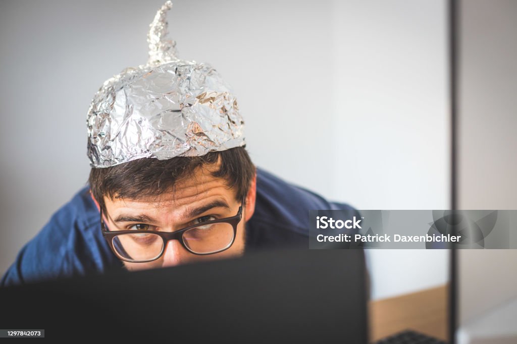 Conspiracy theory concept: young man is wearing aluminum head Young man is wearing aluminum cap, conspiracy theory concept QAnon Stock Photo