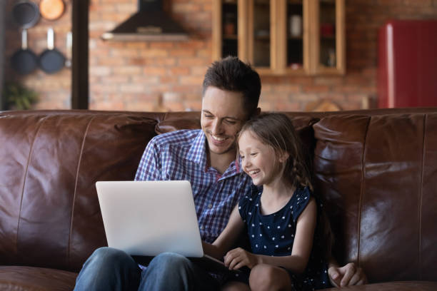 istock Laughing father and little daughter using laptop at home together 1297843788