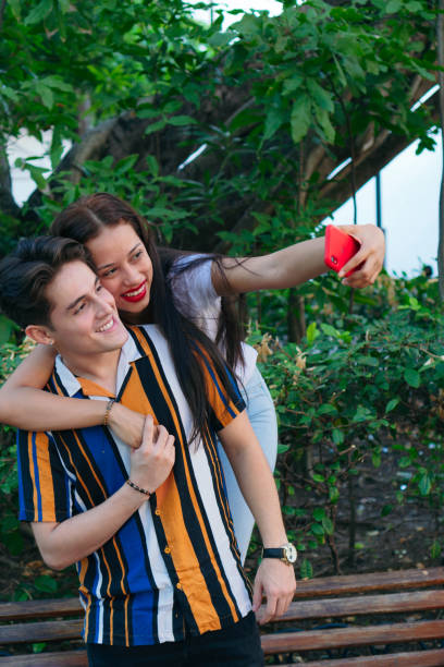 istock Latin man with girlfriend taking a selfie at park 1297848933