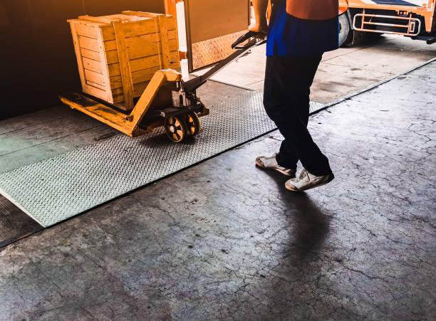 Worker driving forklift loading shipment carton boxes goods on wooden pallet at loading dock from container truck to warehouse cargo storage in freight logistics, transportation industrial, delivery trabajador conduciendo carretilla elevadora de carga cajas de cartón de mercancías en palet de madera en el muelle de carga desde el camión contenedor hasta el almacenamiento de carga de almacén en logística de carga, transporte industrial, entrega