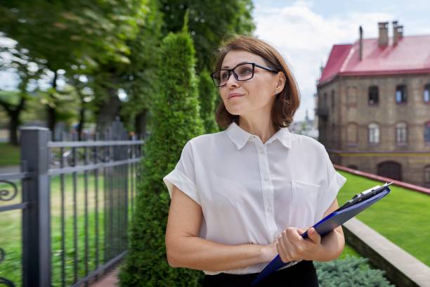 portret pewnego siebie uśmiechniętej bizneswoman, nauczycielki, doradcy z papierowymi dokumentami schowka - private secretary zdjęcia i obrazy z banku zdjęć