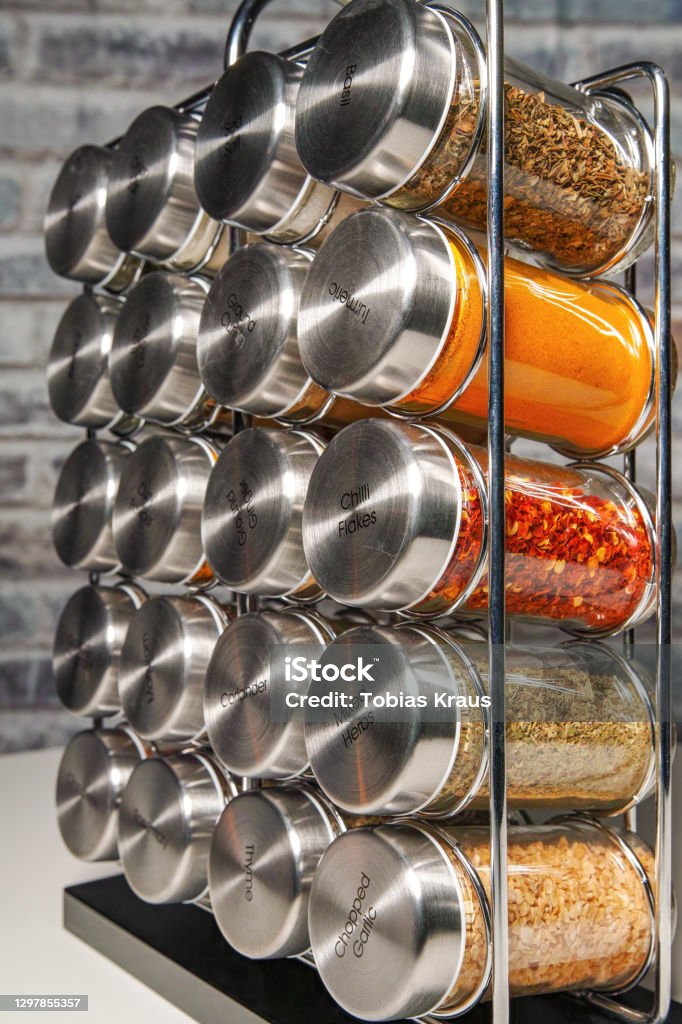 A metal spice rack with many glass bottles filled with different spices A metal spice rack with many glass bottles filled with different spices, studio shot Kitchen Stock Photo