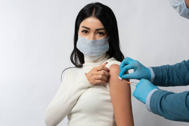 istock Woman wearing protective mask gets vaccinated to protect against coronavirus 1297856294