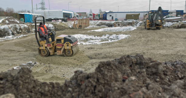 Loader excavator, bulldozer and roller work on construction site. Machines perform excavation work. Compaction of soil and rubble for residential buildings. Construction work