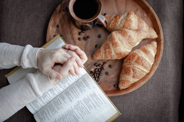 istock Hands in prayer on open bible with coffee mug and croissants 1297863040