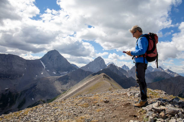 Male mountaineer reaches mountain summit He looks at digital tablet, plans route ahead environment computer cloud leadership stock pictures, royalty-free photos & images