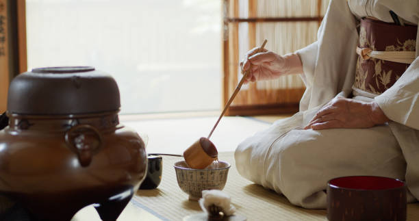Tea Ceremony Hostess Ladling Water Into Small Bowl A senior Japanese woman dressed in kimono, acting as the host of a traditional Japanese tea ceremony at a Chashitsu in Tokyo, Japan. traditional ceremony photos stock pictures, royalty-free photos & images