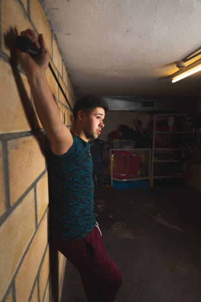 istock Young caucasian man doing exercise stretching a rope at the garage 1297864848