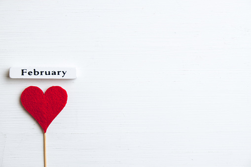 Heart near month february on wooden background with copy space.