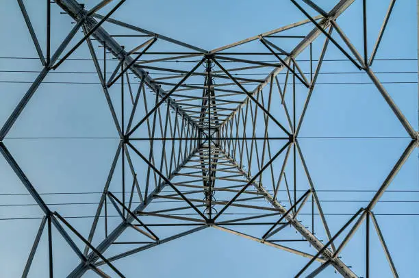 Photo of Square diagonals of a Transmission tower with a blue sky.